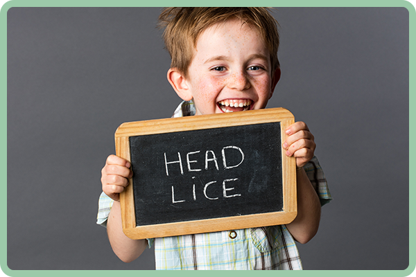 A boy has a black board in his hand that has head lice word on it