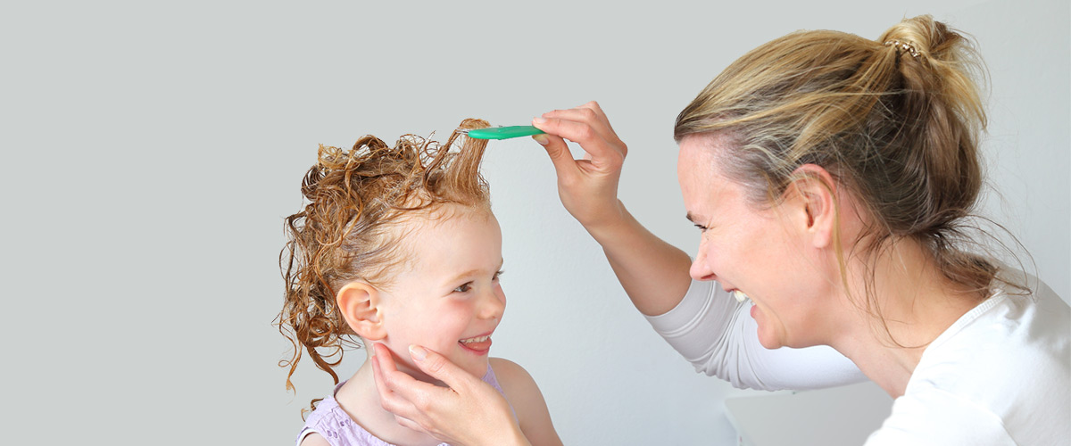 Mom checking her daughter's hair for head lice